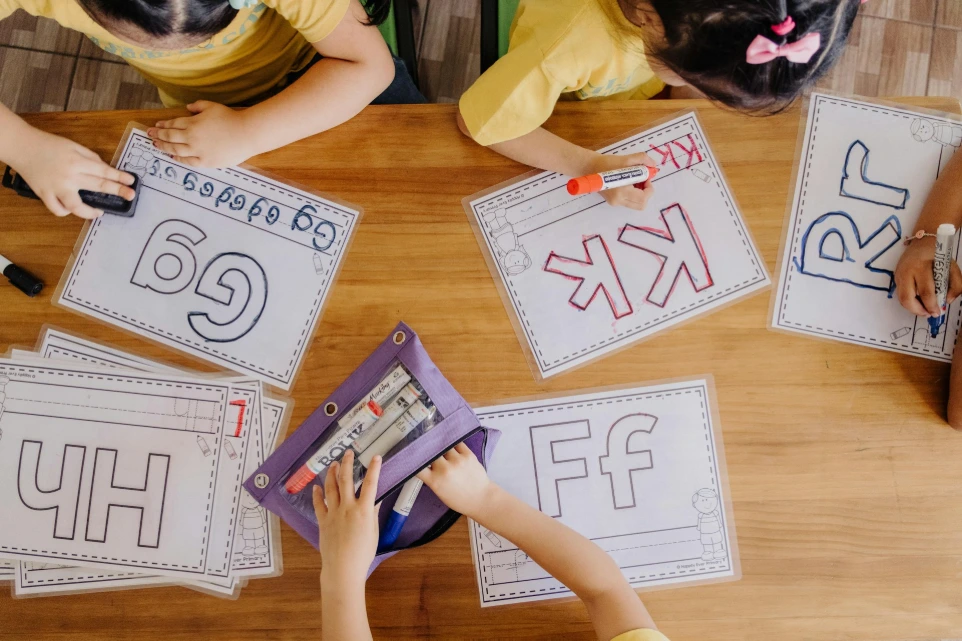 A group of children sitting at a table with paper cut outs